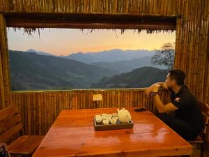 a man sitting at a table with a view of mountains at Mâm Xôi Homestay 