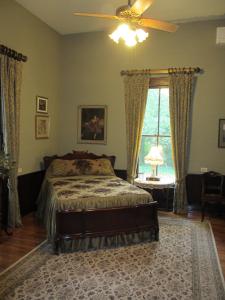 1 dormitorio con 1 cama, ventilador de techo y ventana en Adair Manor Bed & Breakfast, en Adairsville