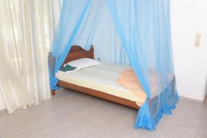 um quarto com uma cama com cortinas azuis em Sunil Lanka Hotel em Aluthgama