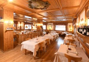 um restaurante com mesas e cadeiras brancas num quarto em Hotel Valgranda Wellness & Spa em Val di Zoldo