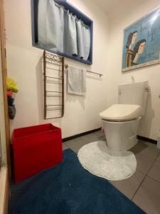 een badkamer met een wit toilet en een rode kruk bij spaceMU in Osaka