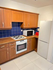 a kitchen with wooden cabinets and a white refrigerator at San Pedro- Anchorage in North Woolwich