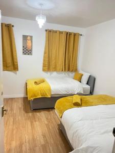 a bedroom with two beds with yellow blankets at San Pedro- Anchorage in North Woolwich