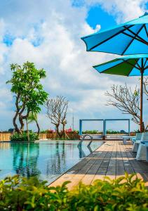 a swimming pool with a table and an umbrella at Rama Residence Padma in Legian