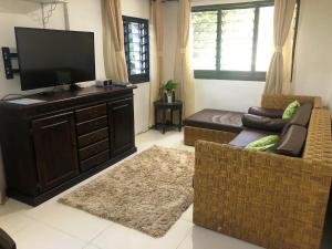 Suva City Accommodation في سوفا: غرفة معيشة مع تلفزيون بشاشة مسطحة وأريكة
