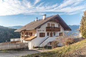 una casa blanca en una colina con una valla en Figisterhof, en Chiusa