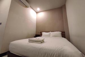 1 dormitorio con 1 cama blanca y 2 toallas en OYO 92089 Hotel Subur, 