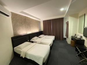 a hotel room with three beds and a television at Just Hotel BP in Batu Pahat