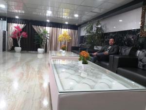 un hombre sentado en un sofá en el vestíbulo en Sohi Residency, en Nueva Delhi