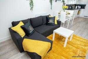 a living room with a black couch and yellow pillows at Hermes Apartment - The Messenger of Town in Southampton