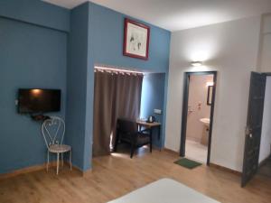 Habitación con pared azul, silla y escritorio. en Divine Inn Couple Friendly Hotel near Sector 51 Metro Station, en Noida