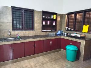 une cuisine avec des armoires rouges et une poubelle bleue dans l'établissement Mount Forest, à Meppādi