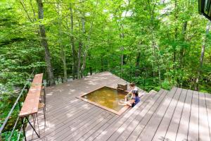 2 bambini seduti su una terrazza con piscina d'acqua di ロックフォレスト北軽井沢 a Kita-karuizawa