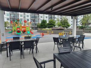 un patio con mesas y sillas y un parque infantil. en Cozy Spacious Home 2 BR SKS Habitat Larkin JB, en Johor Bahru