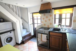 a kitchen with a stove and a sink and a staircase at Jasmine Cottage, Buxton Norfolk, Sleeps 4 in Norwich