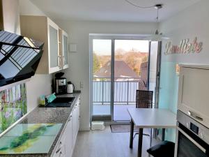 eine Küche mit einem Tisch und Blick auf einen Balkon in der Unterkunft SONNIGE KUSCHELZEIT in Niebüll