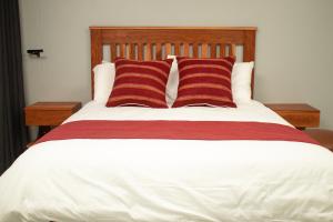 a bed with two red and white striped pillows at R Executive Apartments in Harare