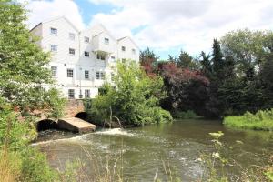 a large white building next to a river at Jasmine Cottage, Buxton Norfolk, Sleeps 4 in Norwich