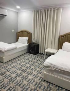 Habitación de hotel con 2 camas y mesa en فندق أباهى3, en Al Hofuf
