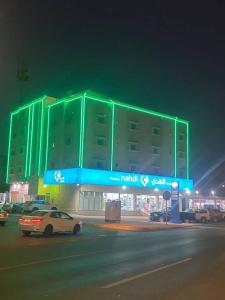 un edificio verde con un coche aparcado delante de él en فندق أباهى3, en Al Hofuf