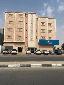 un gran edificio con coches estacionados frente a él en فندق أباهى3, en Al Hofuf