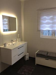 La salle de bains est pourvue d'un lavabo blanc et d'un miroir. dans l'établissement Kleine Villa Marleen, Ferienwohnung, à Schneverdingen