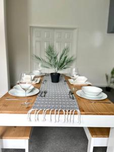 una mesa de madera con platos y gafas y un puesto de mesa en Great location, spacious 3 bedroom house en Pallion