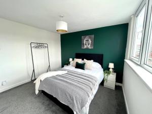 a bedroom with a large bed with a green wall at Great location, spacious 3 bedroom house in Pallion