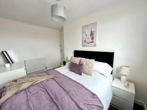 ein Schlafzimmer mit einem großen Bett mit einer lila Decke in der Unterkunft Great location, spacious 3 bedroom house in Pallion