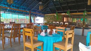 a restaurant with blue tables and chairs and a bar at Banorupa Kuakata hotel in Kuākāta