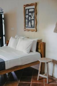 a bed with white pillows and a stool in a room at The Kip in Ahangama