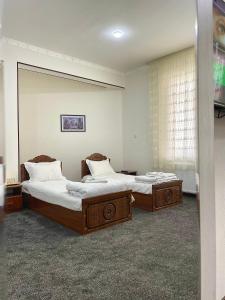 two twin beds in a room with a window at CHO'PON OTA Hotel in Samarkand