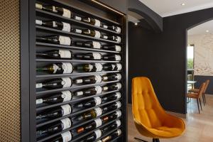 een muur van wijnflessen in een wijnkelder met een gele stoel bij Maison Cabotte in Beaune