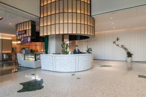 Un uomo seduto al bancone in una hall di SSAW Boutique Hotel Zhijiang a Hangzhou