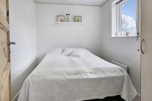1 dormitorio con 1 cama blanca y ventana en Sommerhus ved Vesterhavet, en Ulfborg