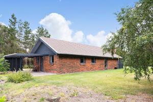 una casa de ladrillo rojo con techo negro en Sommerhus ved Vesterhavet, en Ulfborg