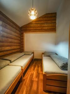 two beds in a room with wooden floors and a chandelier at Koliba Pod Skalami in Súľov-Hradná