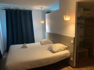 um quarto de hotel com uma cama com lençóis brancos e almofadas em Hôtel Saint Roch Montpellier Centre em Montpellier