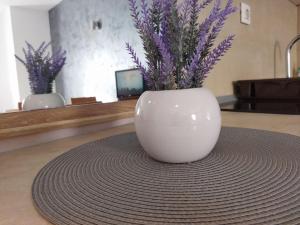 a white vase with purple flowers in it on a table at Apartman Masa Kopaonik in Kopaonik