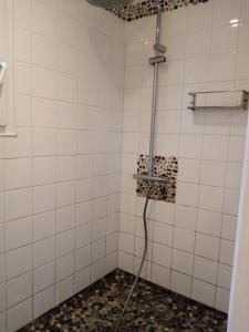 La salle de bains est pourvue d'une douche avec un tuyau et de carrelage blanc. dans l'établissement Saint Jacut de la mer, maison avec jardin., à Saint-Jacut-de-la-Mer