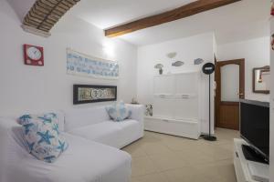 uma sala de estar com um sofá branco e uma televisão em Casa Vacanza Il Murales em Loceri