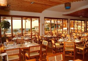 a restaurant with wooden tables and chairs and windows at Dubai Marine Beach Resort & Spa in Dubai