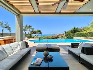 a patio with a couch and a table and a pool at Luxury Villa in Sani, Halkidiki, Greece in Sani Beach