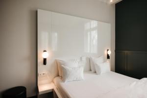 1 dormitorio con 1 cama blanca grande con almohadas blancas en Hotel & Spa Savarin - Rijswijk, The Hague en Rijswijk