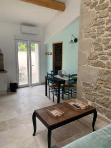 uma sala de estar com uma mesa e uma parede de pedra em LA MAGNANERIE em Grillon