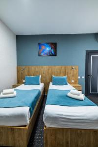 two beds in a room with blue walls at BOBUR Hotel in Tashkent