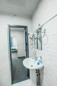 a white bathroom with a sink and a mirror at BOBUR Hotel in Tashkent