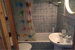 a bathroom with a sink and a shower curtain with dinosaurs on it at Son Parc Menorca recién reformado! in Son Parc