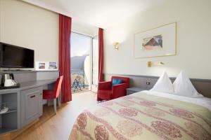 a hotel room with a bed and a desk and a window at Seehotel Waldstätterhof Swiss Quality in Brunnen