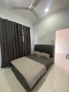een slaapkamer met een groot bed en zwarte gordijnen bij Tok Mek Homestay in Setiu